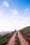 Young woman walking on dirt path country road on the hill at eve