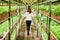 Young woman walking down greenhouse with leafy greens.