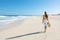 Young woman walking on empty wild beach with white sand and blue sky in Corralejo, Canary Islands