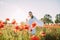 Young woman walking and enjoying among flowering poppies