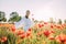 Young woman walking and enjoying among flowering poppies