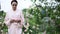 Young woman in walking in garden among blooming pink rose