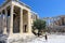 A young woman walking by herself admiring the glorious ancient Greek Old Temple of Athena atop the Acropolis, in Athens