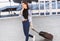 Young woman walking with luggage suitcase and talking smartphone, vacations, travel and active lifestyle concept