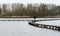 Young woman walking over wooden path from a birdhouse in the lake in the Flemish nature reserve Het Vinne, Zoutleeuw