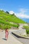 Young woman walking on panoramic path along green vineyards on hills by Lake Geneva, Vaud, Switzerland. Famous Lavaux wine region