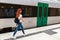Young woman walking railway platform along train