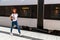 Young woman walking railway platform along train