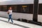 Young woman walking railway platform along train