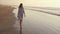 Young woman walking on sea shore during sunset