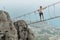 Young woman walking on suspended wooden bridge in mountains on high altitude looking amazing view