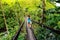 Young woman walking on suspension bridge over Wainibau stream, Lavena Coastal Walk, Taveuni Island, Fiji