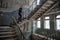Young woman walking up by stairs at the abandoned building at the ghost town Chernobyl