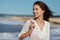 Young woman walking in water wearing white beach dress