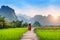 Young woman walking on wooden path with green rice field in Vang Vieng, Laos