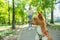 A young woman walks with an African basenji dog on a leash in the park.