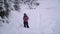 A young woman walks alone through a snowy forest. Young pretty tourist sneaks through the snow drifts. She looks around