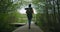 A young woman walks along a road in the woods with a backpack in slow motion. A female traveler in a yellow sweater and