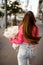 Young woman walks away from the camera with a bouquet of peonies in her hands