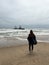 Young woman walks at the beach near sunken trawler, shipwreck. Old ship Zeila.