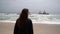 Young woman walks at the beach near sunken trawler, shipwreck. Old ship Zeila.