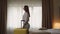 Young woman walks into cozy hotel room carrying suitcase