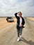 Young woman walks on highway in desert. Girl on center of the road, barefoot.