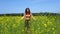 A young woman walks in a rapeseed field and enjoys nature