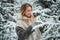 A young woman walks through a winter coniferous forest in search of a beautiful christmas tree for her home.