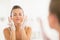 Young woman washing face in bathroom