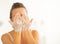 Young woman washing face in bathroom