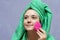 Young woman washing face with silicone pink brush and cleansing foam. Cosmetic products