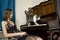 The young woman is watching cat walking on piano