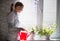 Young woman watering indoor flowers