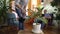 Young woman watering plant in modern home man reading from tablet