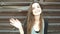 Young woman waving hand saying hello against metal fence of brown color. Smiling happy cheerful caucasian girl having