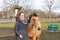 Young woman in a wax coat with her two 1 year old stallions in the pasture. Two curious horses heads