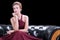 Young woman wear red dress fashion posing and sitting on black sofa looking at camera on isolated white background.