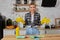 Young woman wearing apron sitting with heap of cleaning sponges indoors