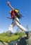 Young woman wearing backpack leaping across river