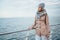 Young woman wearing beige coat, scarf, hat and backpack