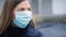 Young woman wearing blue disposable virus face mouth nose mask, closeup portrait, blurred background. Coronavirus covid-19