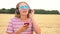 Young woman wearing blue sunglasses in a field listening to music on wireless headphones