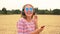 Young woman wearing blue sunglasses walking in a field listening to music on wireless headphones