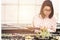 A young woman wearing a checkered shirt is checking sales progress on a tablet at the cactus. A beautiful Asian woman looks at her