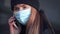 Young woman wearing disposable blue virus face mouth nose mask talking on mobile phone. Closeup detail, can be used during