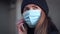 Young woman wearing disposable blue virus face mouth nose mask talking on mobile phone. Closeup detail, can be used during