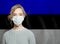 Young woman wearing a face mask with estonian national  flag. Flu epidemic and virus protection concept