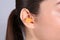 Young woman wearing foam ear plug on grey background, closeup