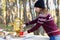 Young woman wearing jersey with hat pouring some tea using vintage russian teapot samovar